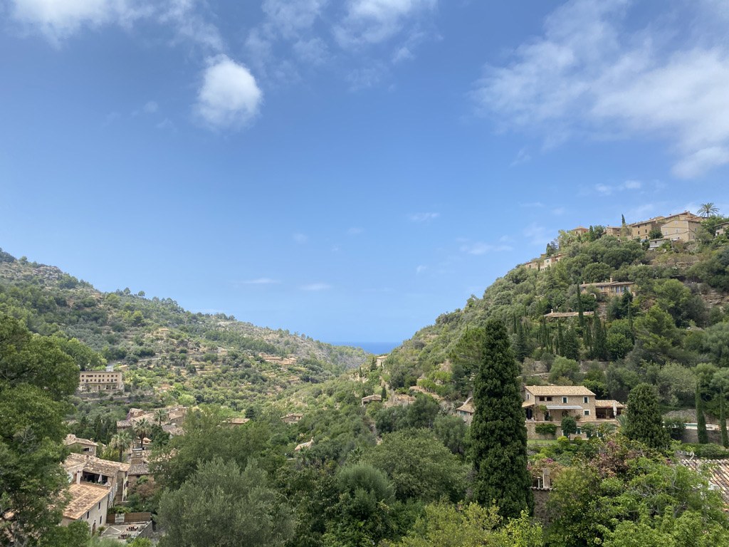 The village of Deià on its green terraced hillside, with stone houses among cypresses and olive trees