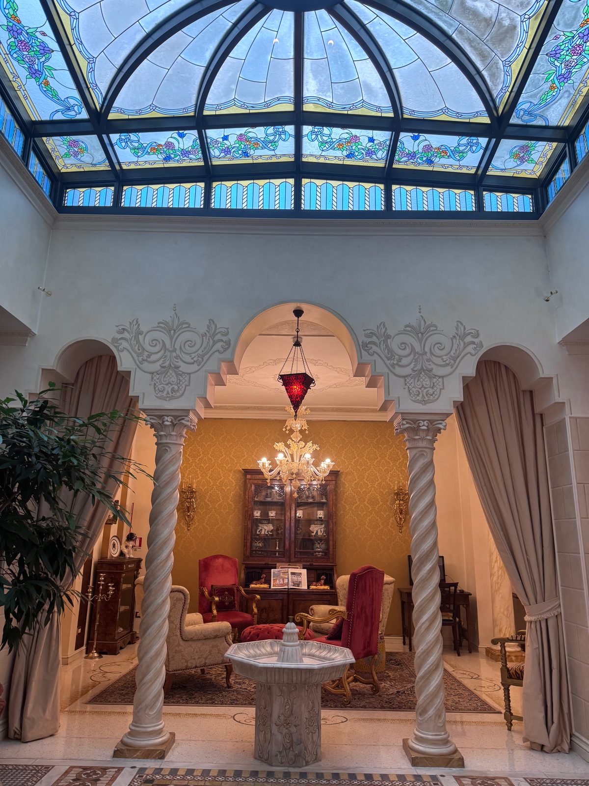 The stained glass roof of the atrium at Aminta, above a sitting room framed by twisted columns
