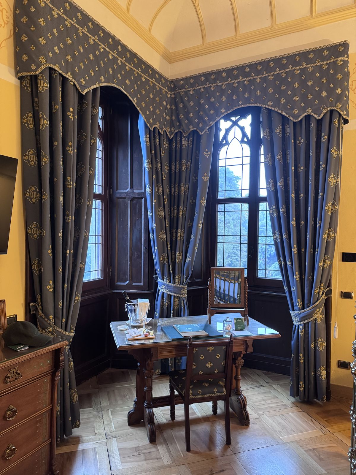 A desk in the bay window of our room at Castello Dal Pozzo, with a bottle on ice and blue curtains