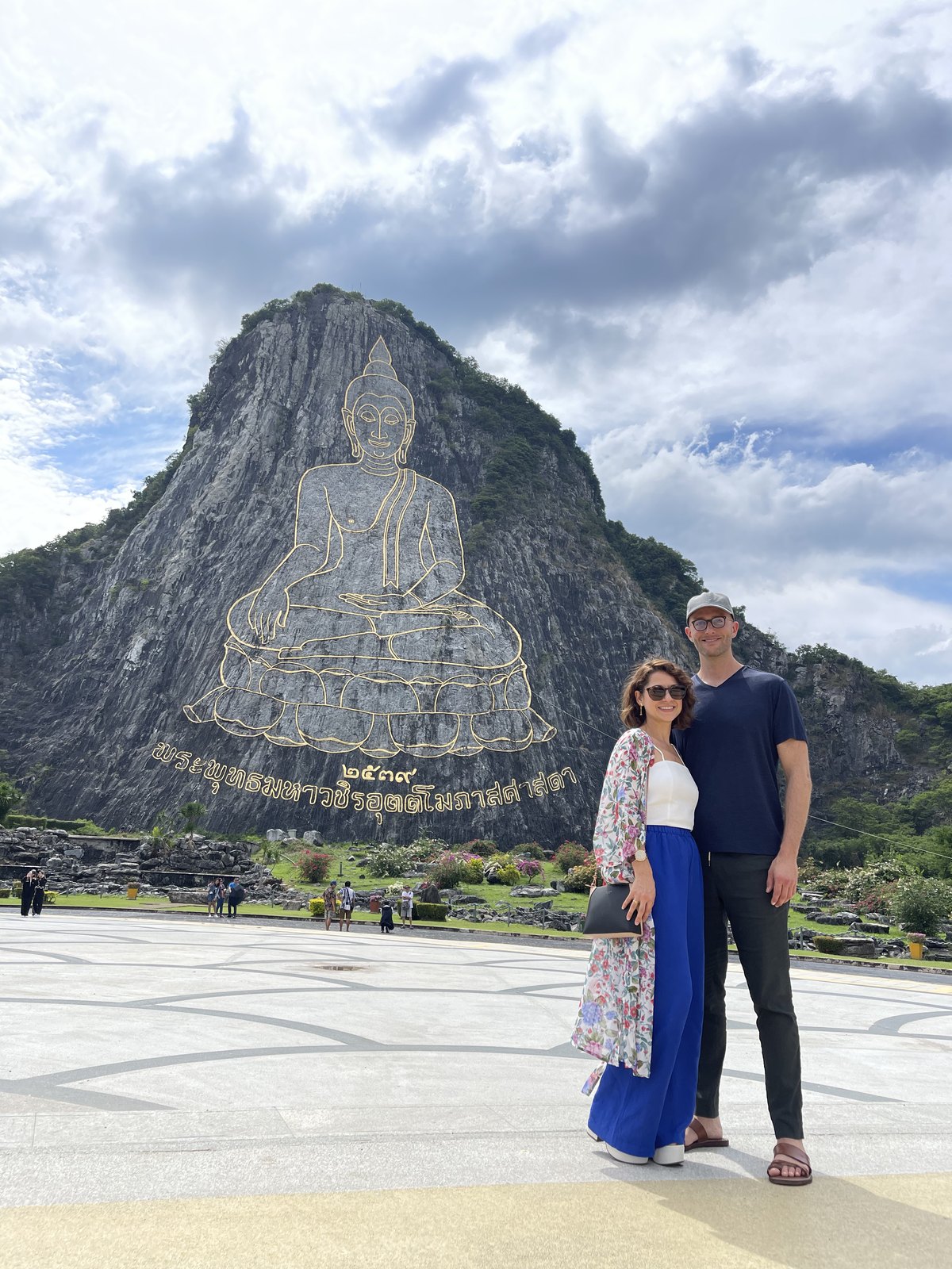 Thomas and Teri in front of the Buddha outlined in gold on the cliff at Khao Chi Chan