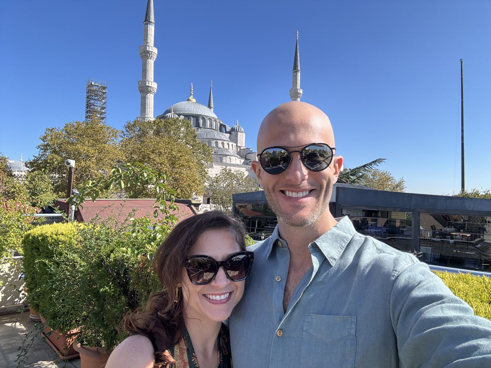 Thomas and Teri in sunglasses on a terrace, with the domes and minarets of the Blue Mosque behind them